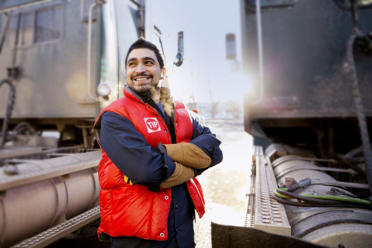 Confident worker standing by semi trucks outdoors