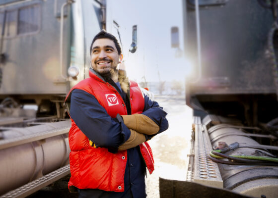 Confident worker standing by semi trucks outdoors